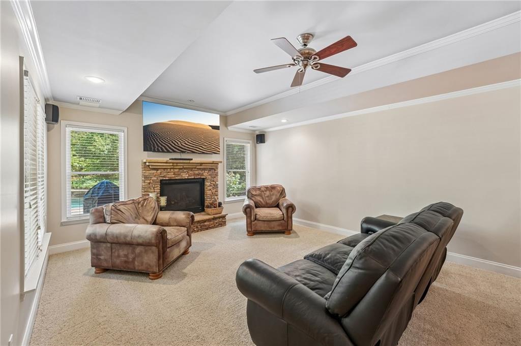 Living room with a stone fireplace, leather seating, and windows overlooking greenery.