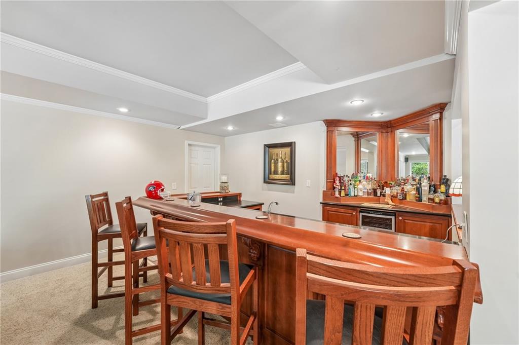 Wet bar with a polished wood counter, high-backed stools, and mirrored shelves stocked with bottles.