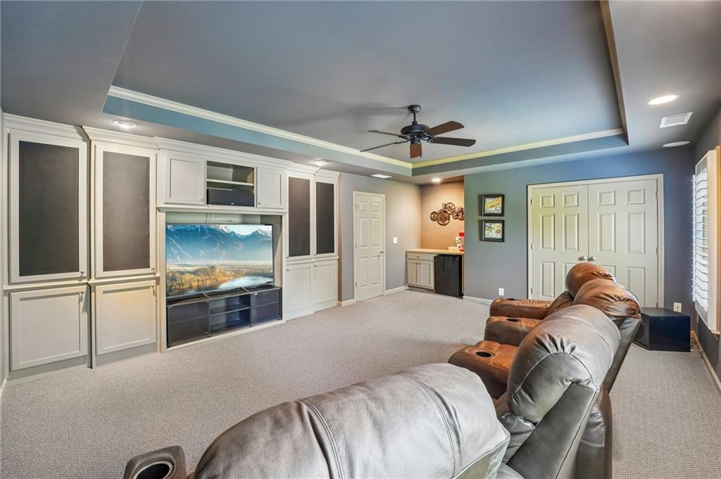 Furnished media room with built-in TV cabinetry, leather recliners, and a small kitchenette.