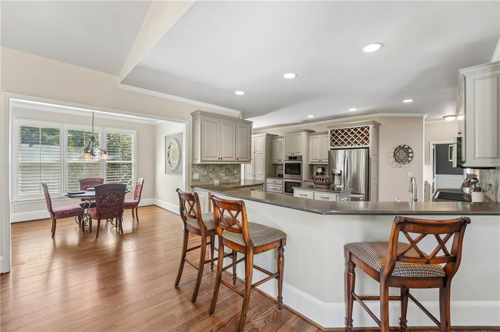 Open kitchen with a curved island and adjoining dining area beside wide windows.