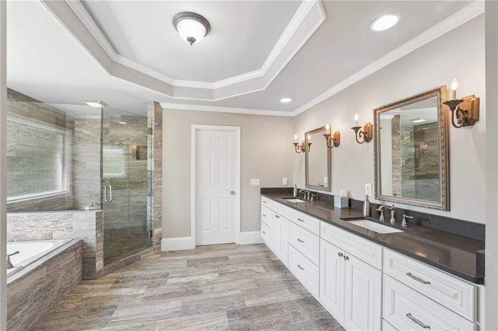 Bathroom with a glass shower, built-in soaking tub, and long double vanity.