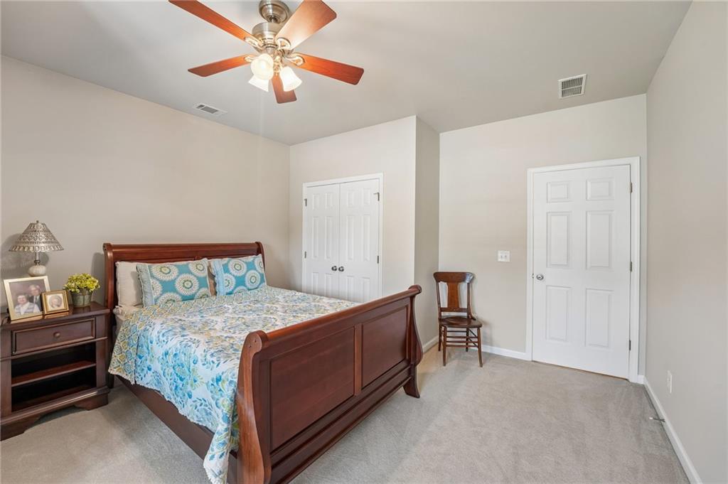 Bedroom with blue floral bedding, dark wood furniture, and a wooden-blade ceiling fan.