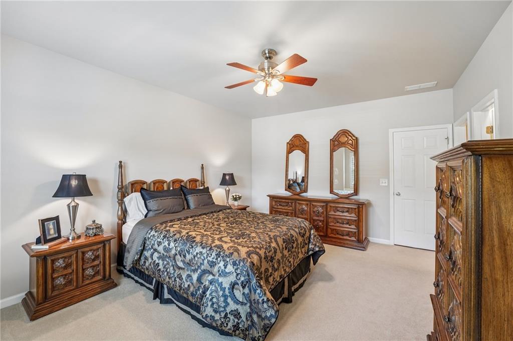 Furnished bedroom with a king bed, ornate dark wood furniture, and a ceiling fan.