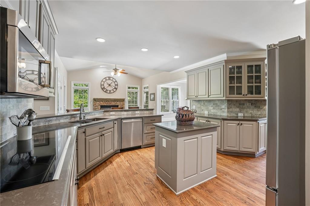 Kitchen with a central island, taupe cabinets, stainless steel appliances, and hardwood floors.