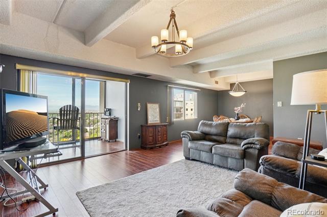 Living room with gray leather sofas, exposed ceiling beams, and sliding glass doors to a balcony.
