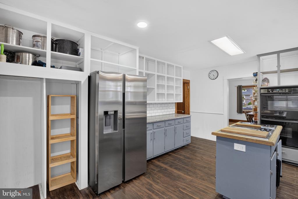 Kitchen with stainless-steel refrigerators, open shelving, gray cabinetry, and a central island.