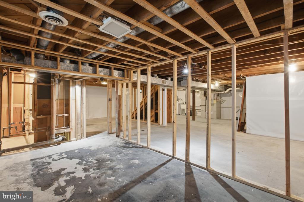 Unfinished basement with exposed framing, concrete floor, and visible utility pipes and ductwork.