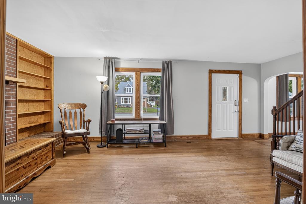 Living room with hardwood floors, brick fireplace, built-in shelving, and a rocking chair.