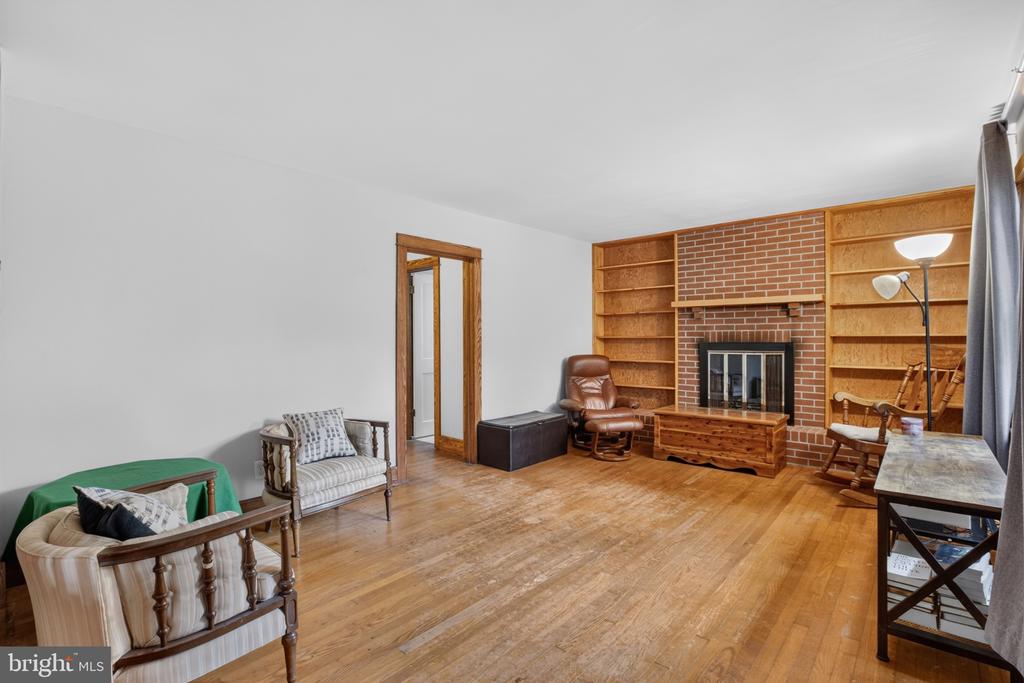 Living room with a brick fireplace, built-in bookshelves, and hardwood floors.