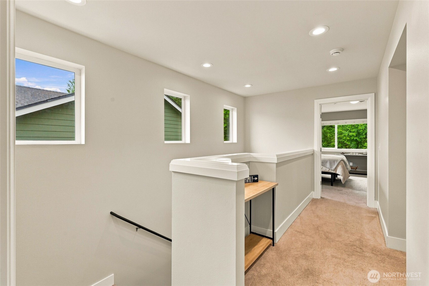 Upstairs landing with a wood-topped built-in bench, narrow windows, and an open view into a bedroom.