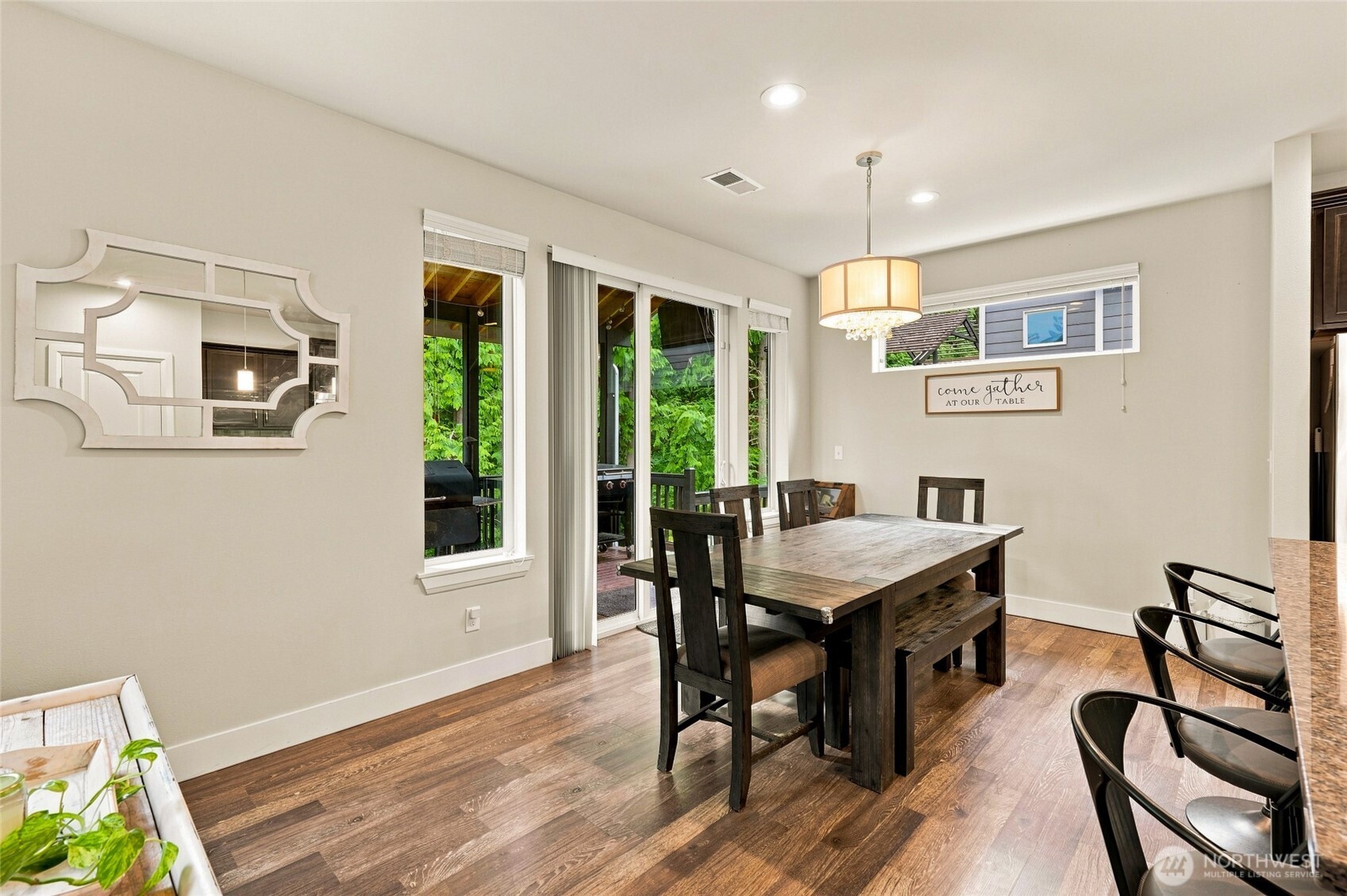 Dining room with a dark wood table, chandelier, and sliding glass doors overlooking greenery.