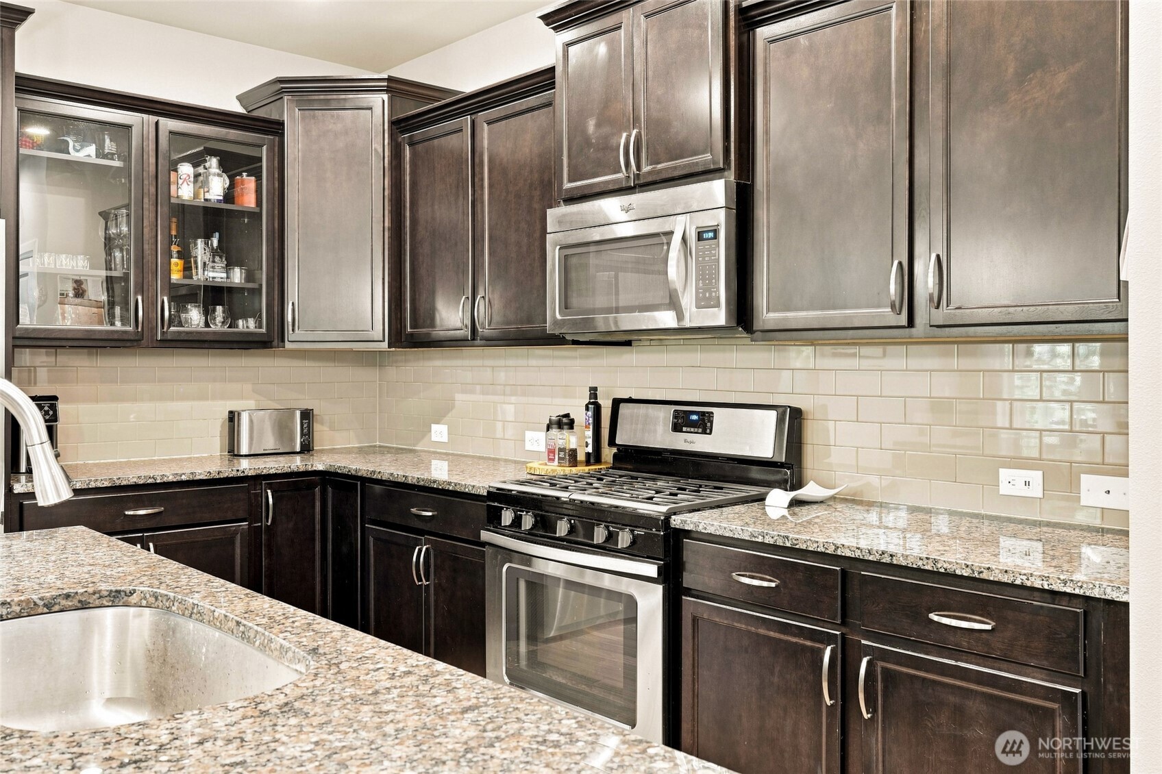 Kitchen with dark wood cabinets, granite counters, and a stainless steel range beneath a built-in microwave.