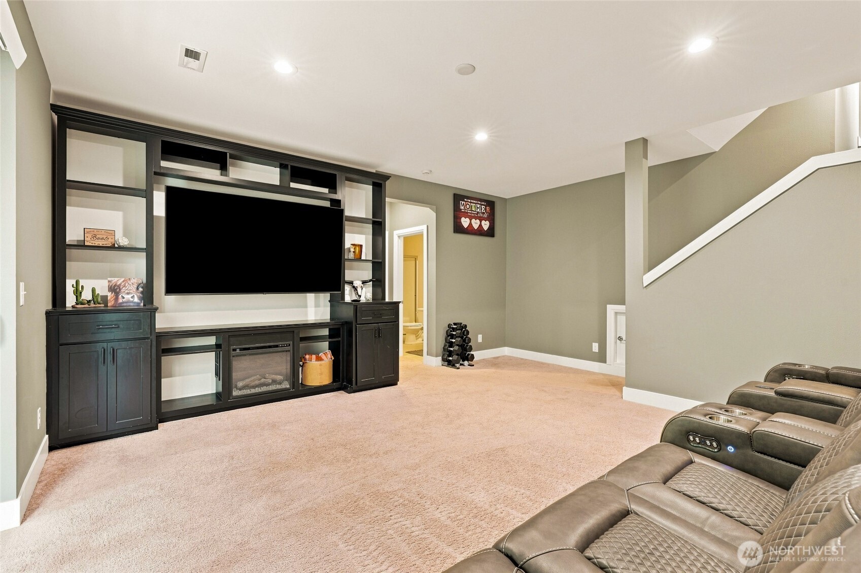 Basement media room with built-in TV cabinetry, fireplace, and leather recliners.