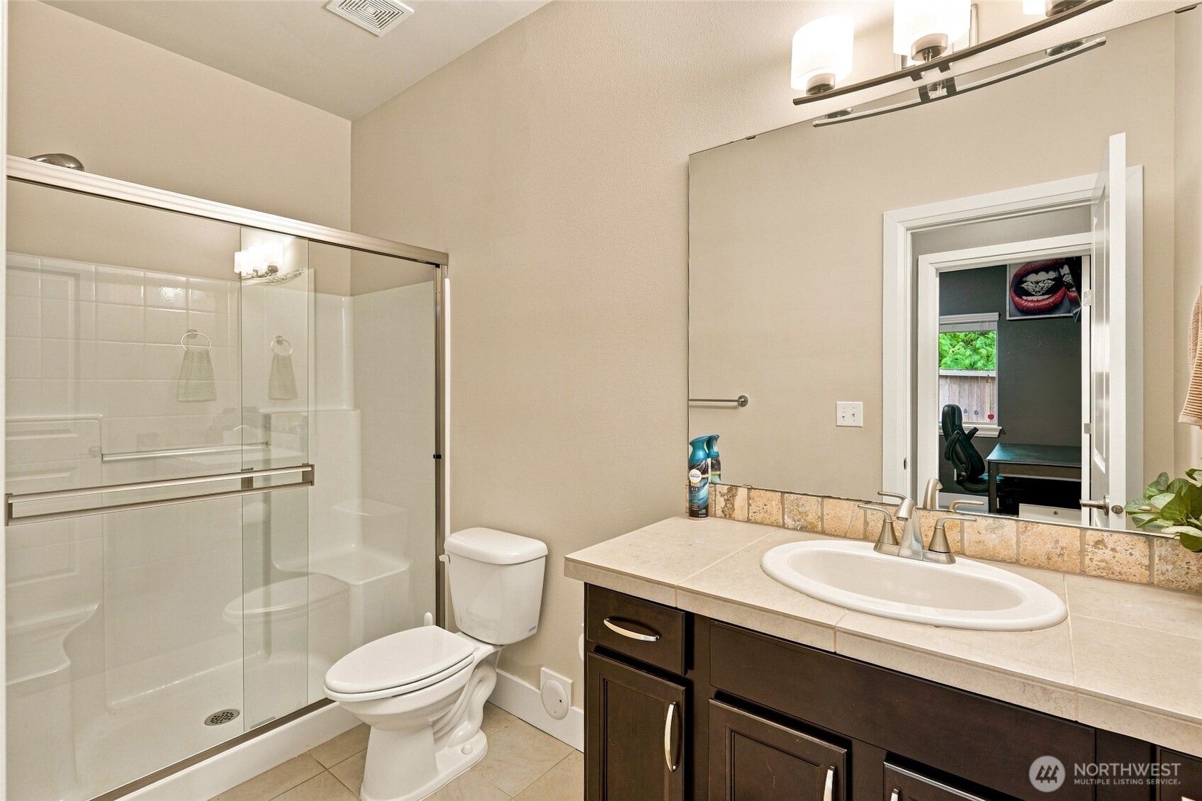 Bathroom with a glass-enclosed shower, tiled vanity, and doorway to an office.