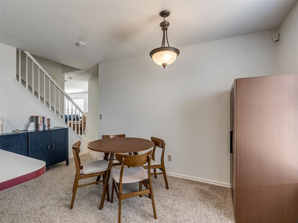Dining room with a round wooden table beside a staircase and dark blue sideboard.