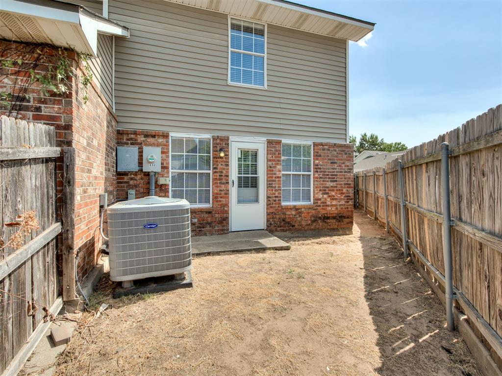 Rear exterior with brick and siding, a fenced side yard, and an outdoor air-conditioning unit.
