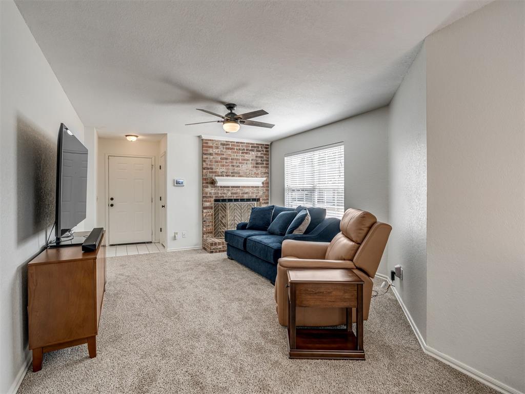 Living room with a brick fireplace, blue sofa, and tan leather armchair.