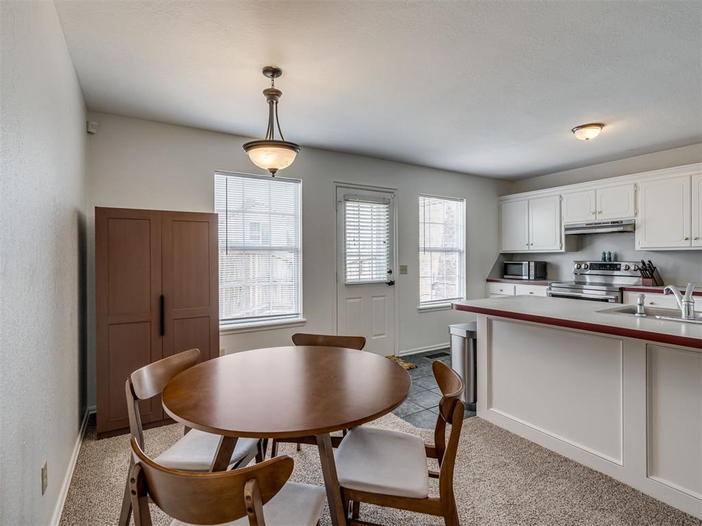 Kitchen and dining area with a round wooden table, white cabinets, and a red countertop.