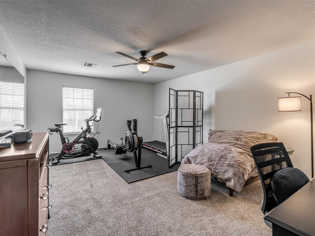 Bedroom with a bed and exercise equipment arranged on black gym mats.