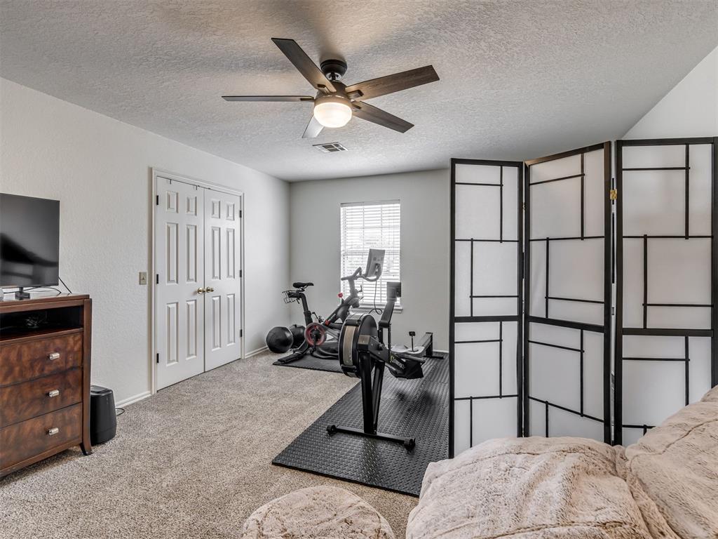 Bedroom with exercise equipment beside the window and a black folding room divider.