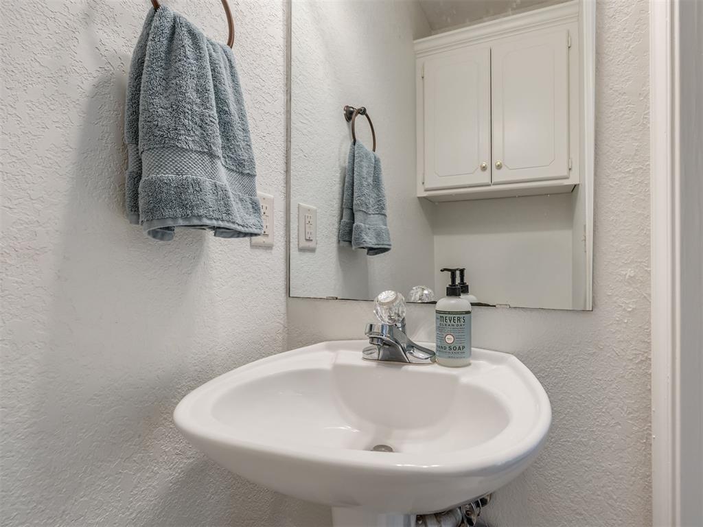 Bathroom sink with a chrome faucet, soap dispenser, and blue-gray towels.