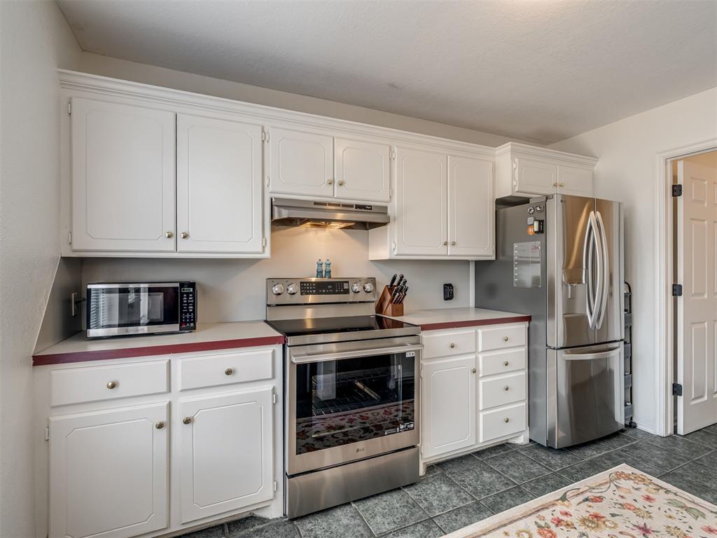 Kitchen with white cabinets, stainless steel appliances, and gray tile flooring.