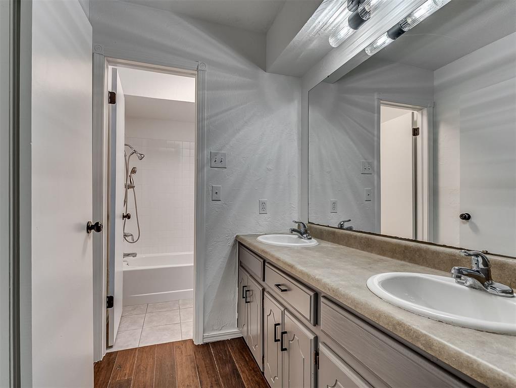 Bathroom with a double-sink vanity and mirror, opening to a tub and shower.