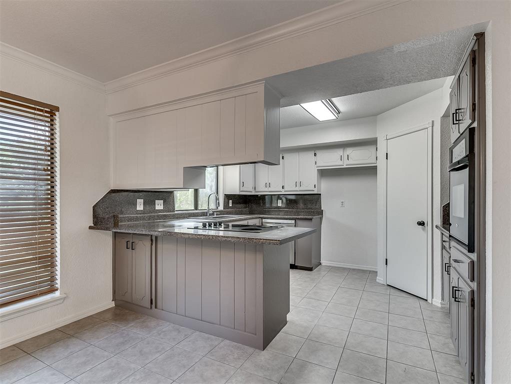 Unfurnished kitchen with gray cabinets, dark countertops, and a breakfast bar.
