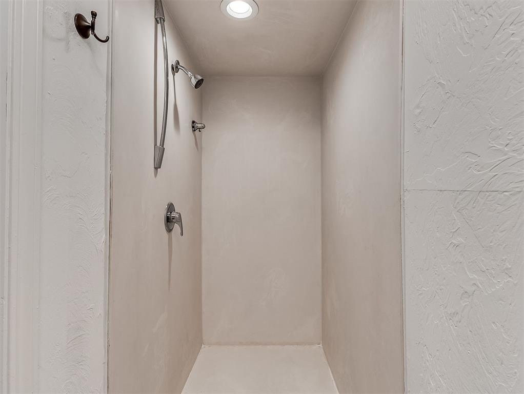 Walk-in shower with a handheld showerhead, chrome fixtures, and a recessed ceiling light.
