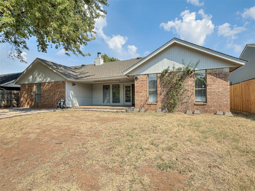 Home’s rear exterior with a covered patio and fenced backyard.