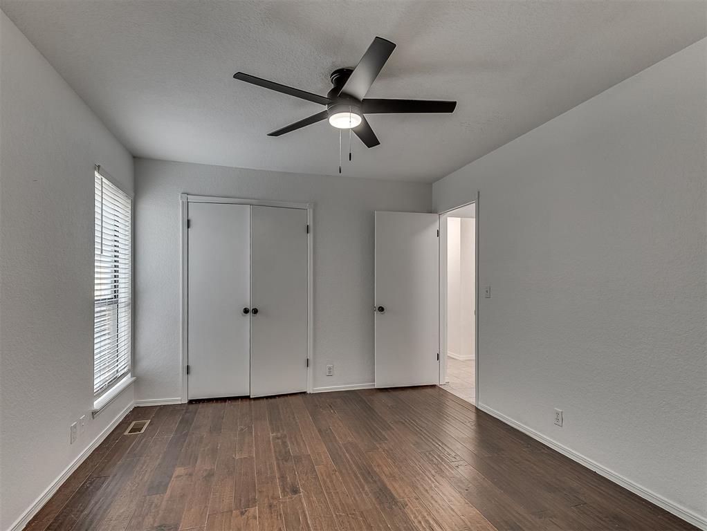 Empty bedroom with dark wood flooring, a ceiling fan, and a double-door closet.