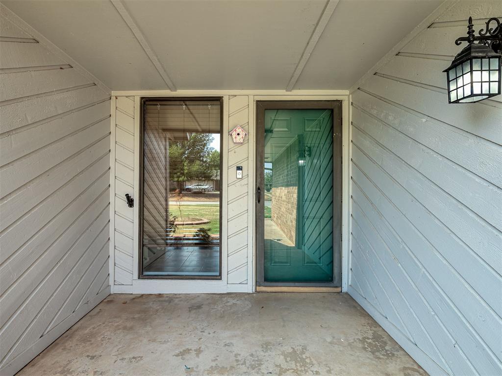 Covered front porch with a teal entry door, tall sidelight window, and black hanging lantern.