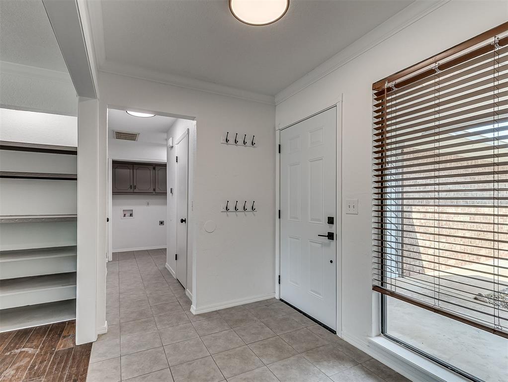 Entryway with tiled floor, wall hooks, built-in shelving, and a window with wooden blinds.