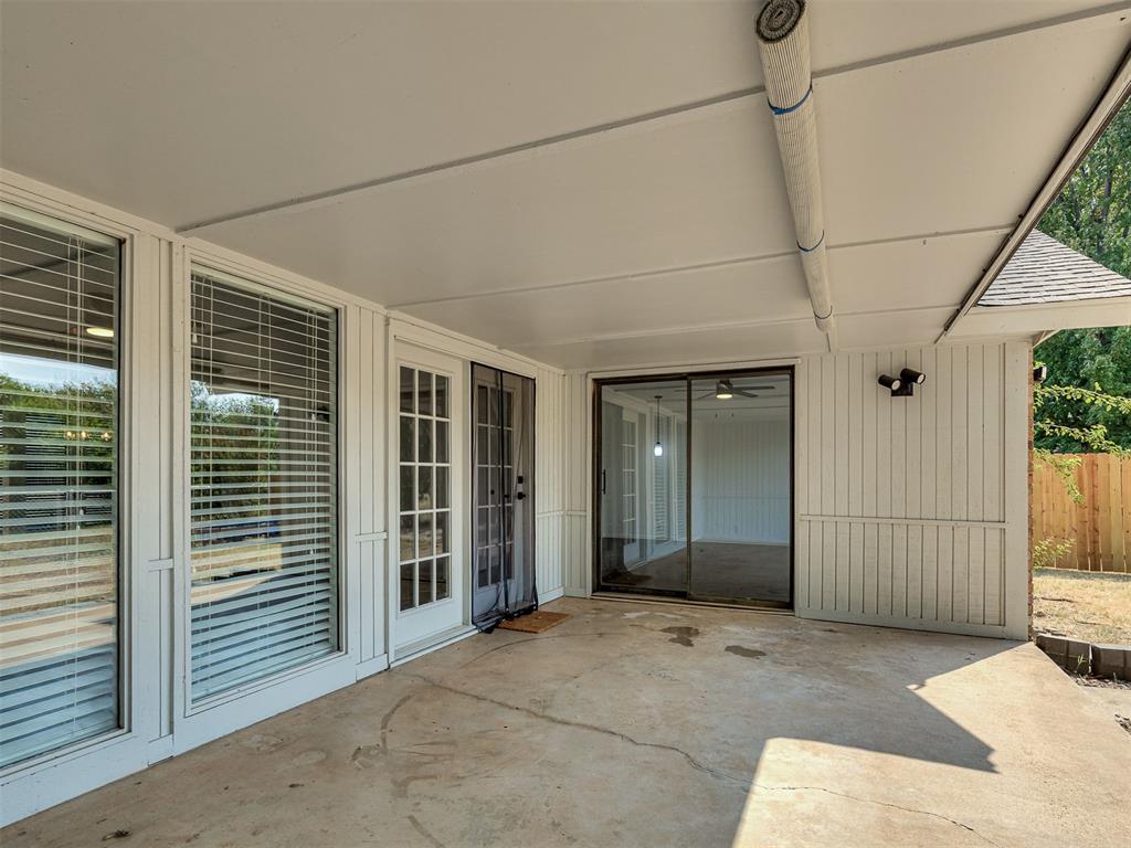 Covered concrete patio with large windows and sliding glass doors.