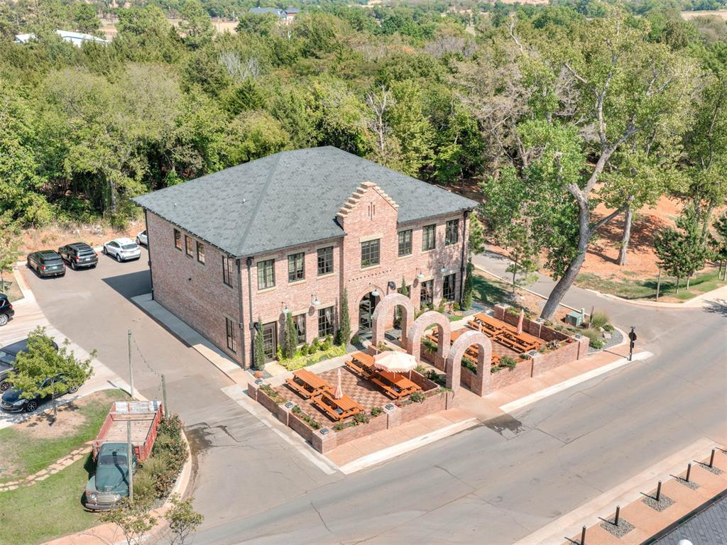 Aerial view of a two-story brick building with a brick-arch patio and picnic tables.