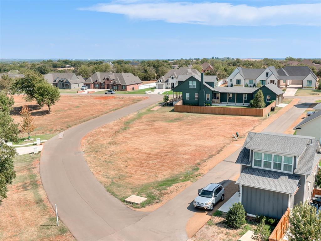 Aerial view of a dark green home beside a large dry, mostly bare lot.
