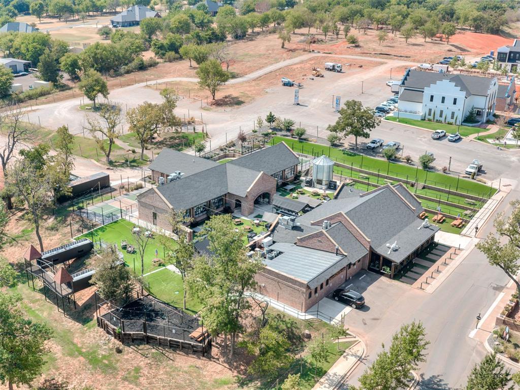 Aerial view of a brick property complex with fenced green grounds and outdoor seating.