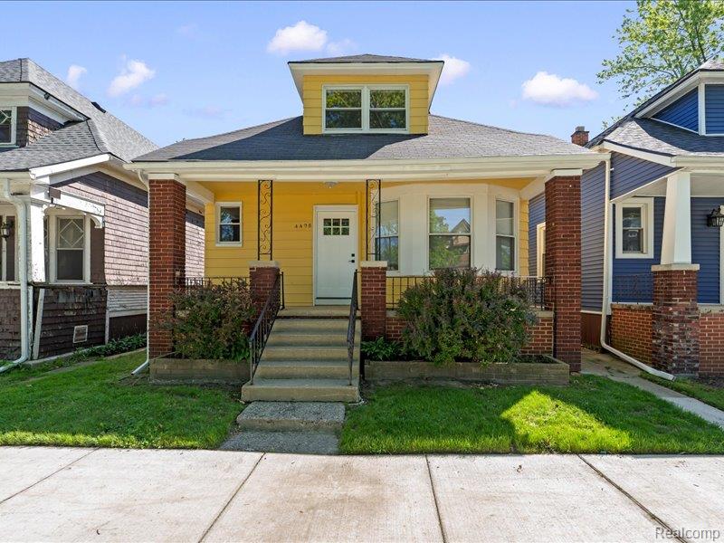 Yellow house with a covered porch, brick columns, and front steps.