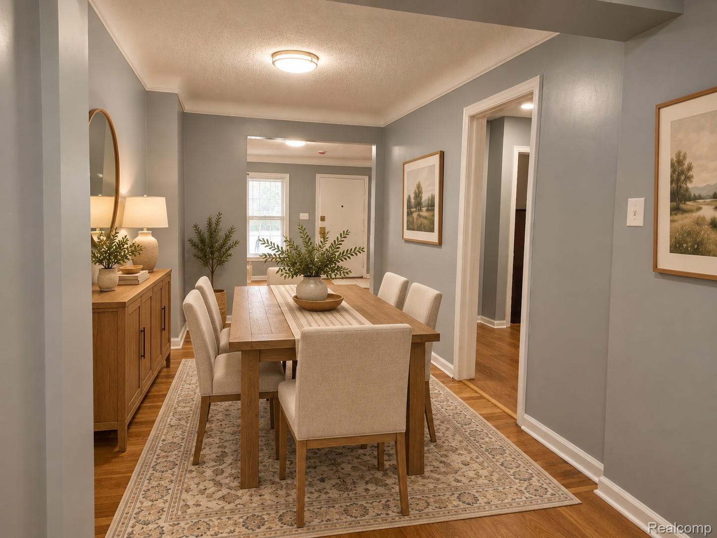 Dining room with a wood table, upholstered chairs, patterned rug, and matching sideboard.