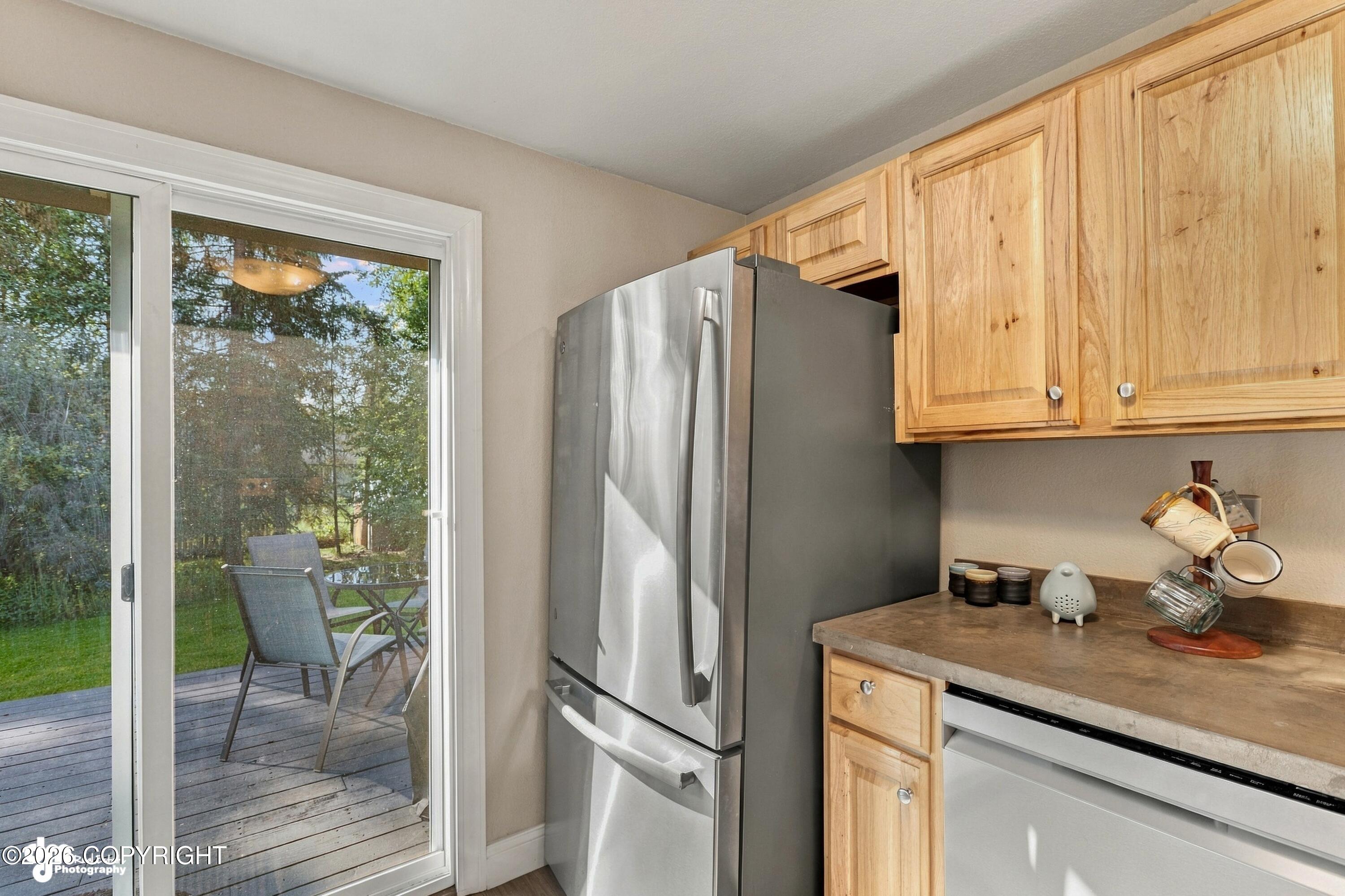 Kitchen with wood cabinets and stainless appliances beside a sliding door to a deck.