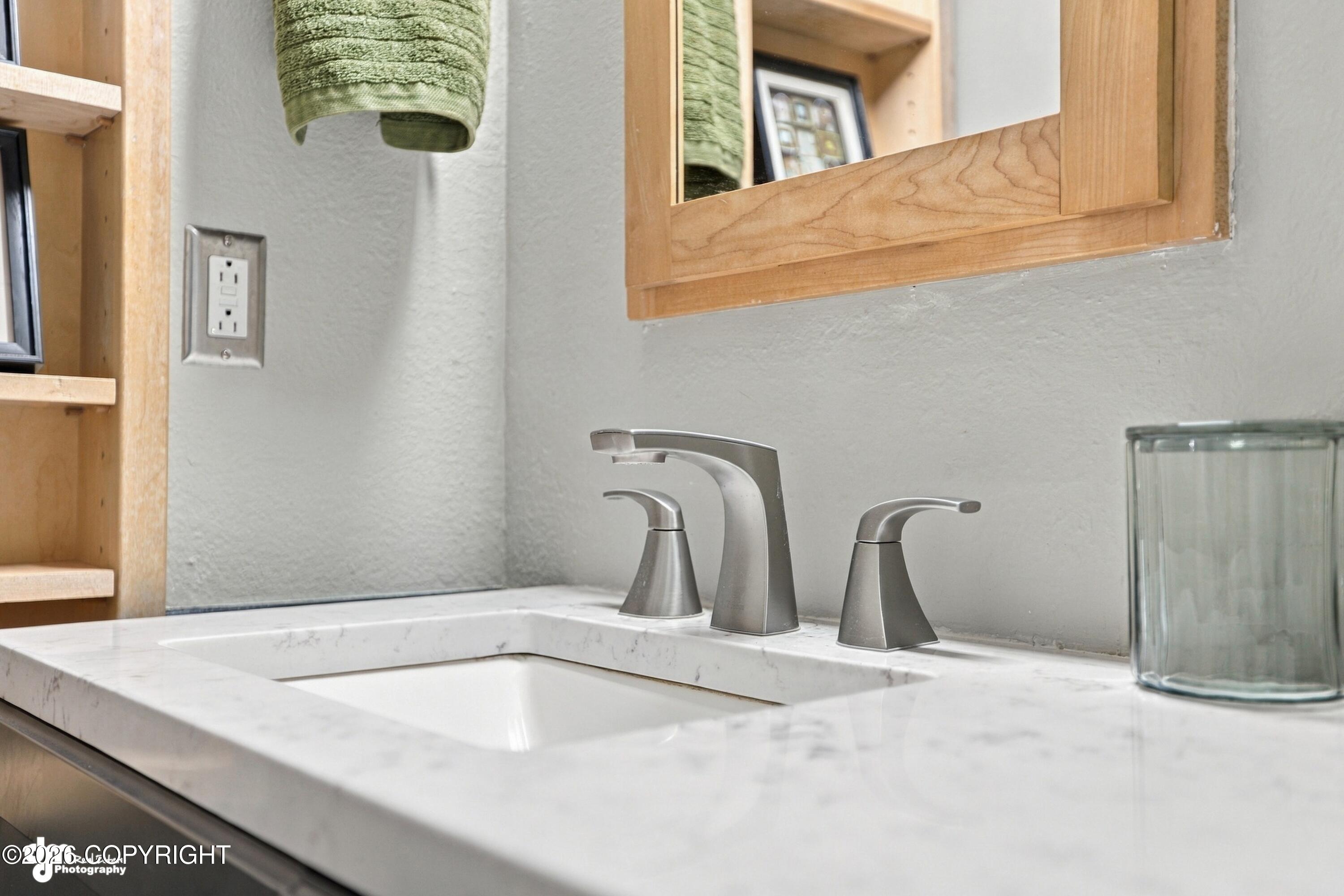 Bathroom vanity with a veined marble countertop, brushed-metal faucet, and wood-framed mirror.