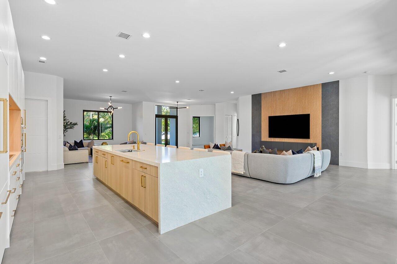 Open-plan kitchen and living room with a large wood-front island and slatted wood TV wall.