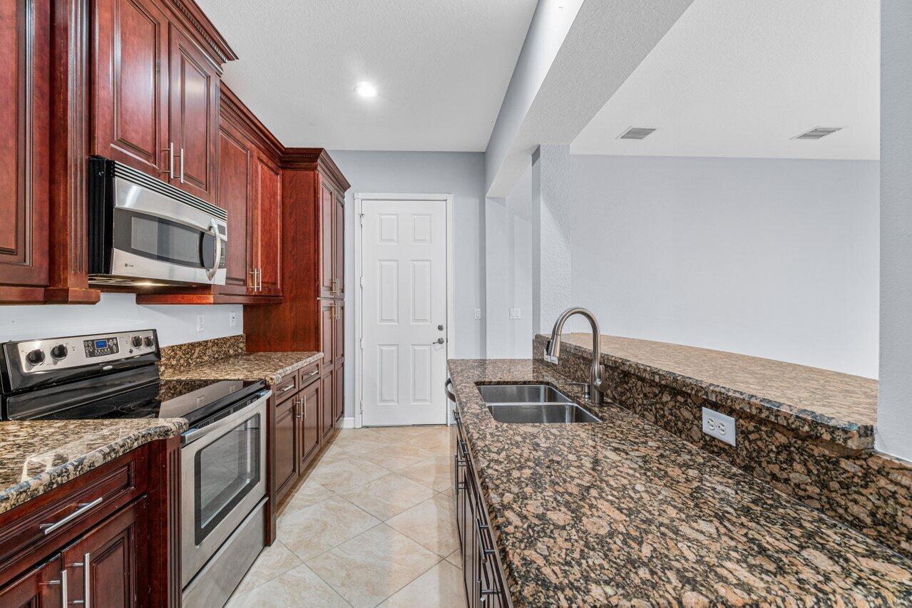 Kitchen with dark wood cabinets, granite counters, stainless steel appliances, and a long peninsula.