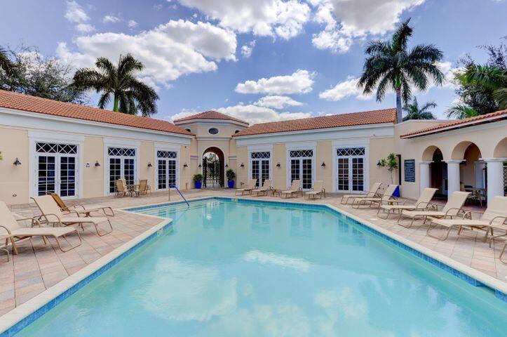 Courtyard swimming pool with tiled deck, lounge chairs, arched openings, and palm trees.