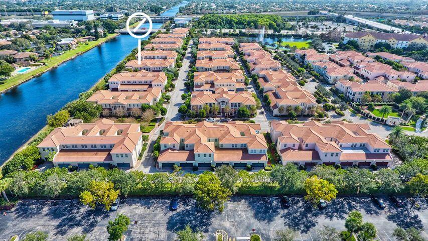 Aerial view of terracotta-roofed townhouses beside a canal, with a white marker highlighting one location.