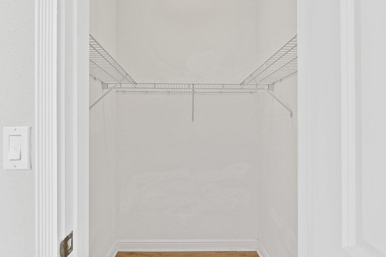 Empty white closet with wire shelving and a wood floor.