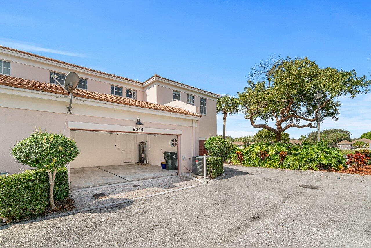 Two-story home with covered garage, terracotta roof tiles, and landscaped driveway.