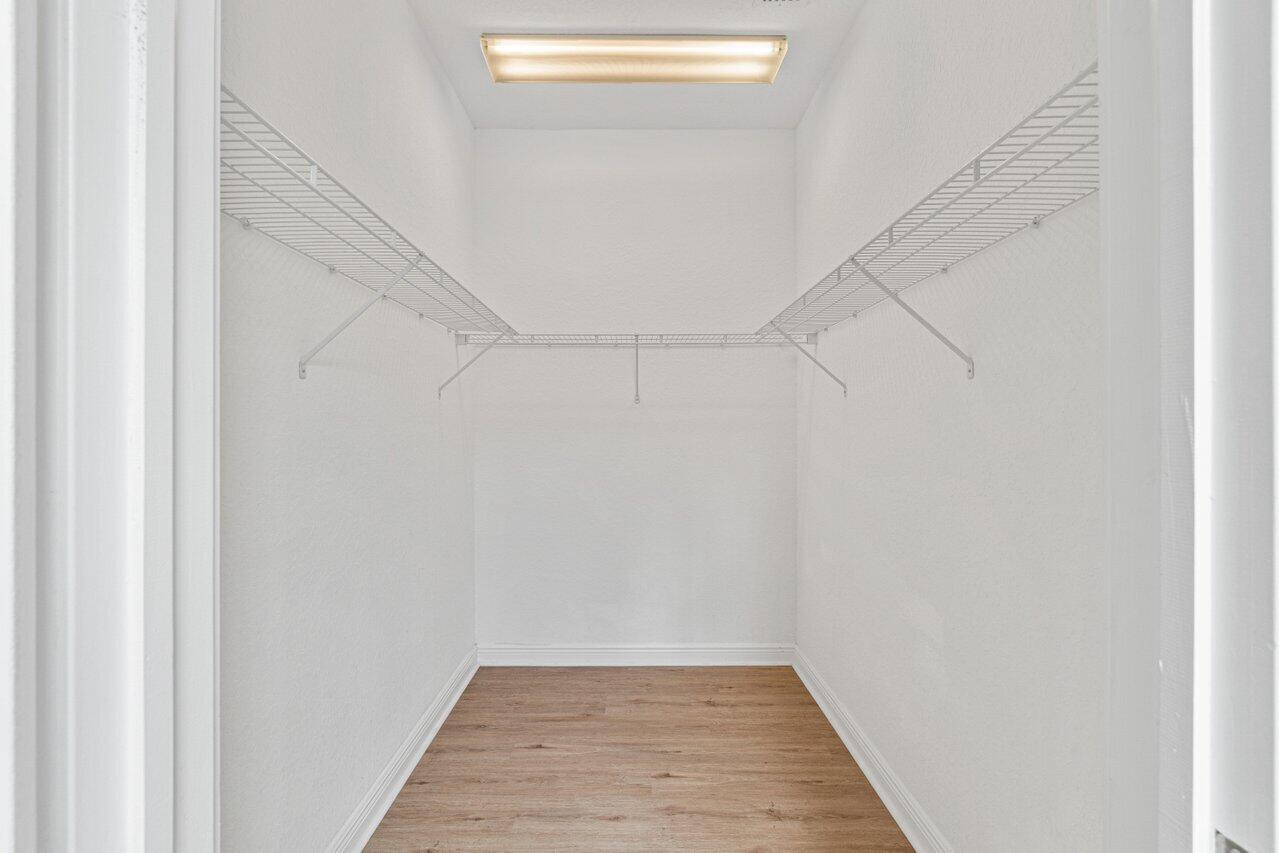 Empty walk-in closet with wire shelving and light wood-look flooring.