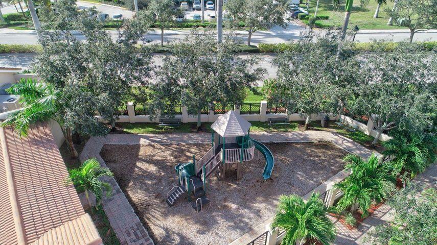 Aerial view of a tree-shaded playground with slides, benches, and paved walkways.