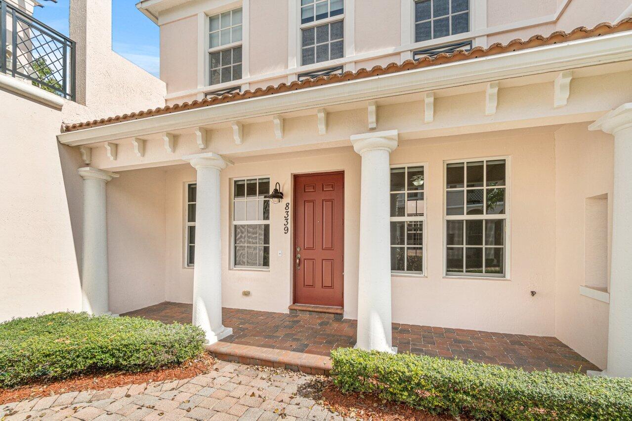 Home entrance with a red front door, white columns, and a covered brick-paved porch.